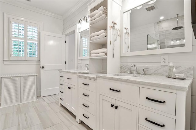 full bath featuring visible vents, vanity, ornamental molding, and tiled shower