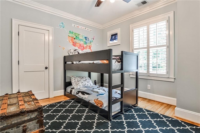 bedroom featuring wood finished floors, ceiling fan, baseboards, ornamental molding, and visible vents