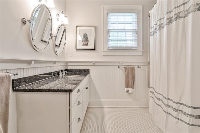 bathroom featuring tile patterned flooring, a wainscoted wall, and vanity