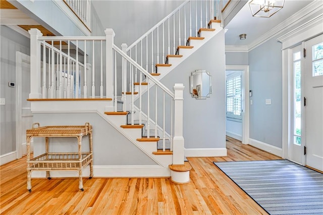 entryway featuring baseboards, a chandelier, wood finished floors, stairway, and crown molding