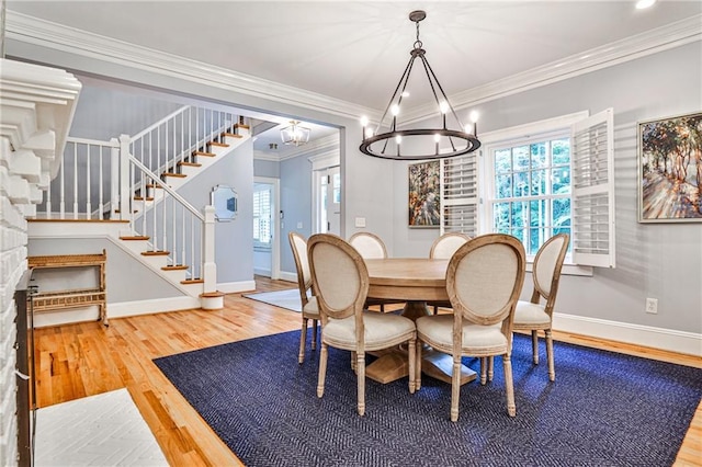 dining space with wood finished floors, ornamental molding, baseboards, stairs, and a notable chandelier