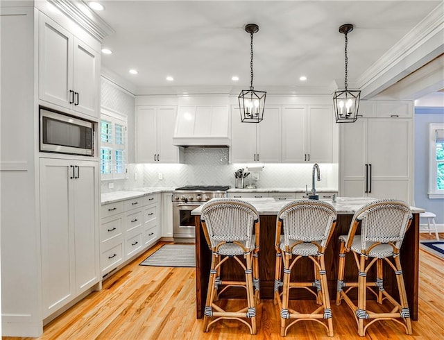 kitchen with custom exhaust hood, light stone counters, crown molding, light wood-type flooring, and appliances with stainless steel finishes