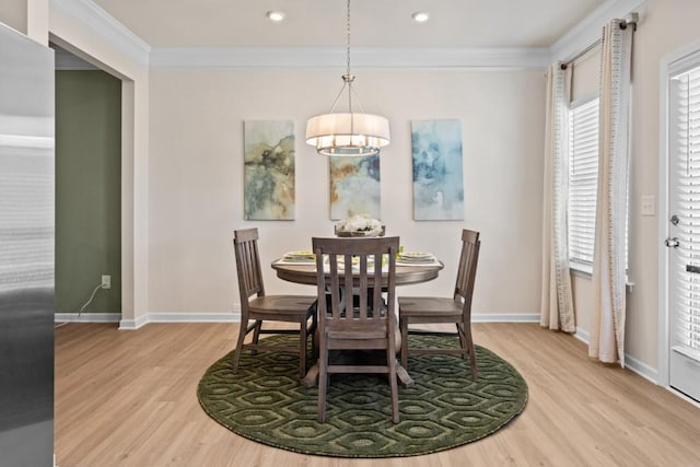 dining area with light wood-style flooring, a notable chandelier, baseboards, and ornamental molding