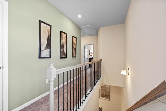 hall with baseboards, an upstairs landing, carpet floors, and attic access