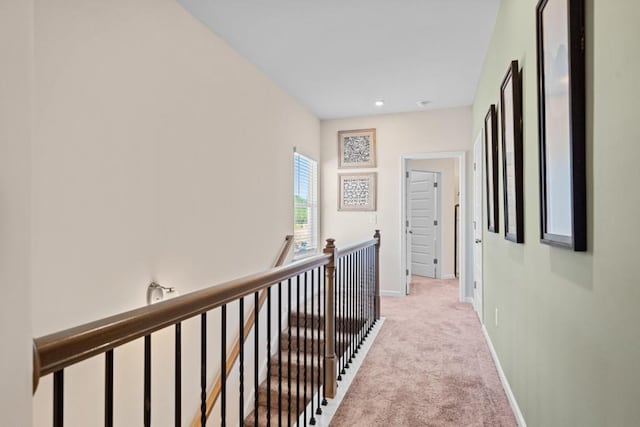 hallway featuring an upstairs landing, baseboards, and light carpet