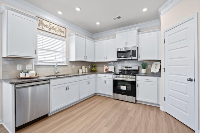 kitchen with visible vents, light wood-type flooring, white cabinets, stainless steel appliances, and a sink