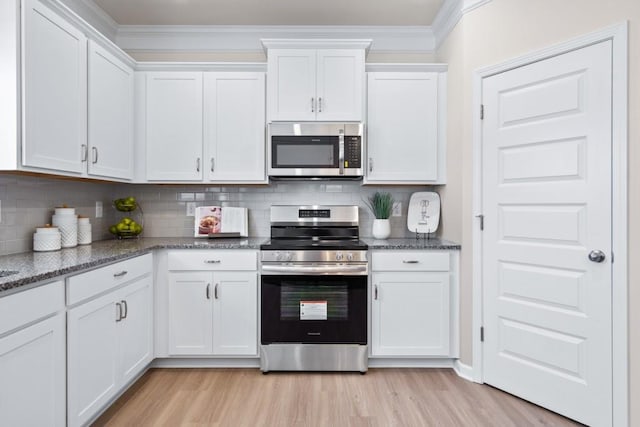 kitchen featuring white cabinetry, decorative backsplash, light wood-style floors, and appliances with stainless steel finishes