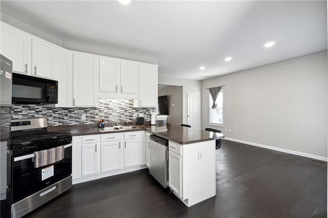 kitchen with appliances with stainless steel finishes, white cabinets, a peninsula, and decorative backsplash