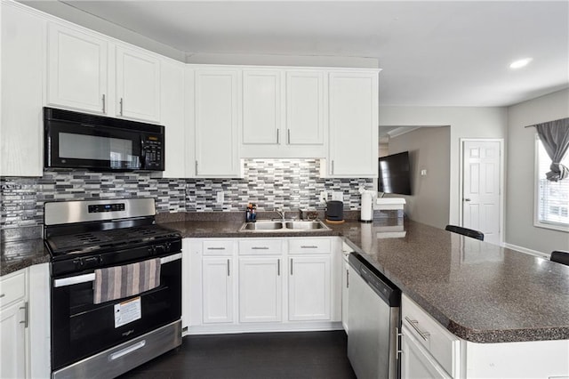 kitchen featuring tasteful backsplash, a peninsula, stainless steel appliances, white cabinetry, and a sink