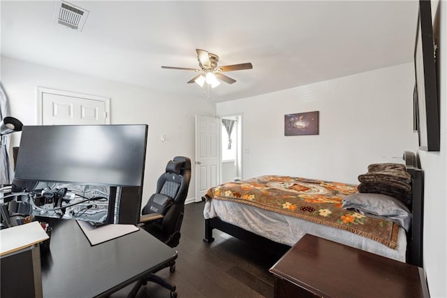 bedroom featuring a ceiling fan, visible vents, and wood finished floors