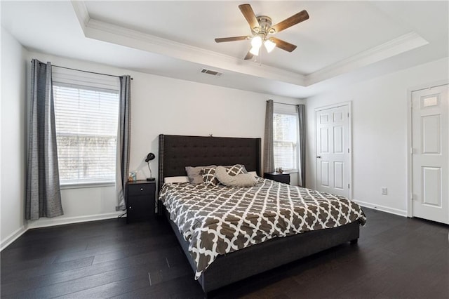 bedroom with a raised ceiling, visible vents, dark wood finished floors, and baseboards