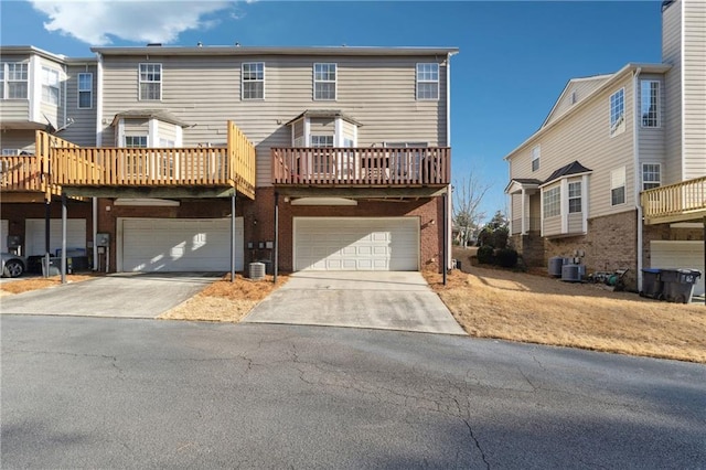 multi unit property with a garage, central air condition unit, concrete driveway, and brick siding