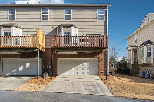 view of front of home featuring a garage, concrete driveway, brick siding, and central AC unit