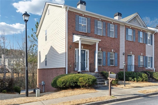 view of property featuring brick siding and a chimney