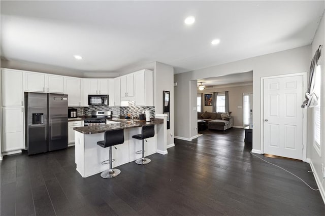 kitchen featuring stainless steel appliances, backsplash, white cabinetry, a peninsula, and a kitchen breakfast bar