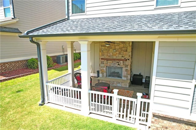 view of patio / terrace featuring central AC unit, fence, and an outdoor stone fireplace