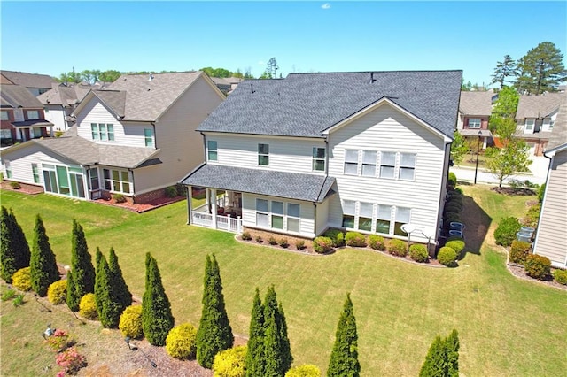 back of property featuring a residential view, a lawn, and roof with shingles