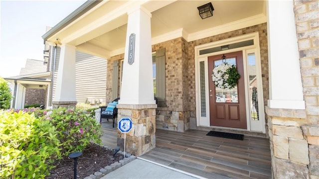 entrance to property with a porch and stone siding