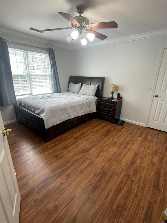 bedroom featuring ornamental molding, dark wood-type flooring, and ceiling fan