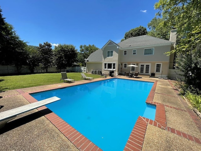 view of swimming pool featuring a yard, a patio, and a diving board