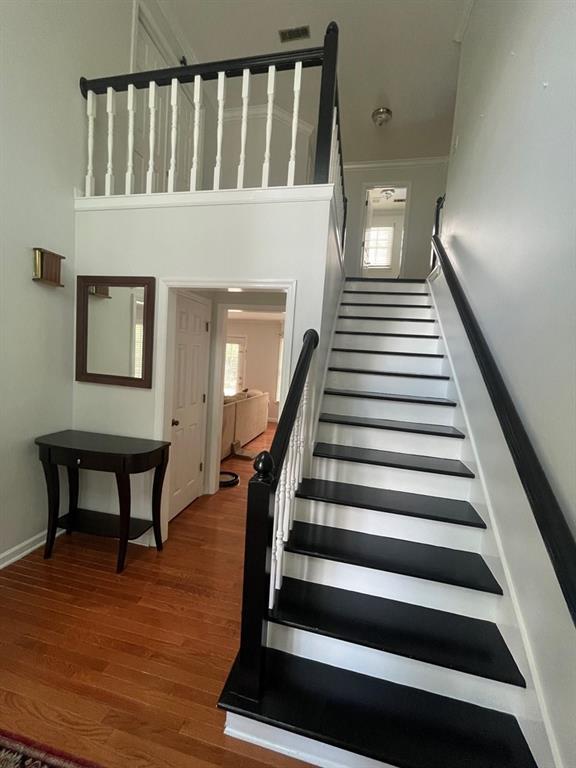 stairway featuring a towering ceiling and hardwood / wood-style flooring