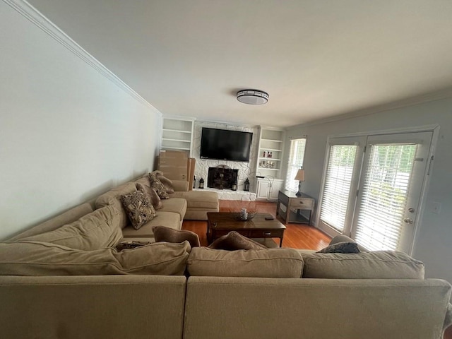 living room with light hardwood / wood-style floors, crown molding, built in features, and a fireplace