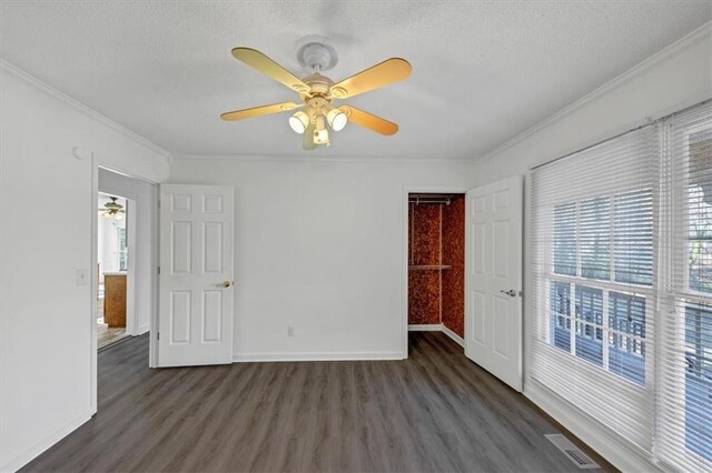 spare room featuring a healthy amount of sunlight, a textured ceiling, ornamental molding, and dark wood-type flooring