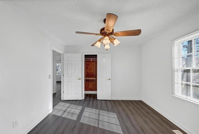 unfurnished room with ceiling fan, dark wood-type flooring, and a textured ceiling