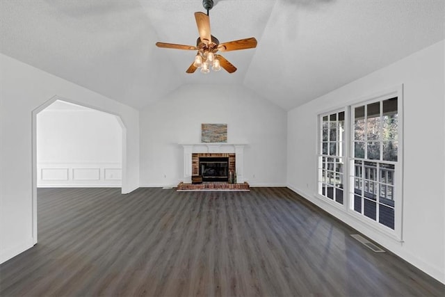 unfurnished living room featuring ceiling fan, a fireplace, dark wood-type flooring, and lofted ceiling