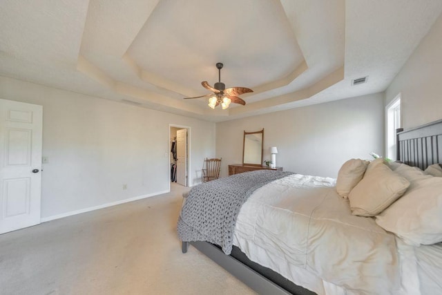 bedroom with ceiling fan, a closet, a walk in closet, and a tray ceiling