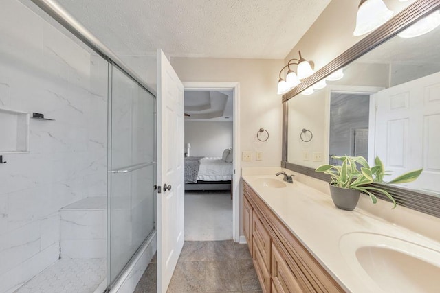 bathroom with a shower with door, vanity, and a textured ceiling