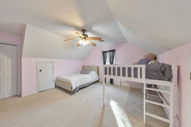 bedroom featuring a textured ceiling, ceiling fan, light carpet, and vaulted ceiling