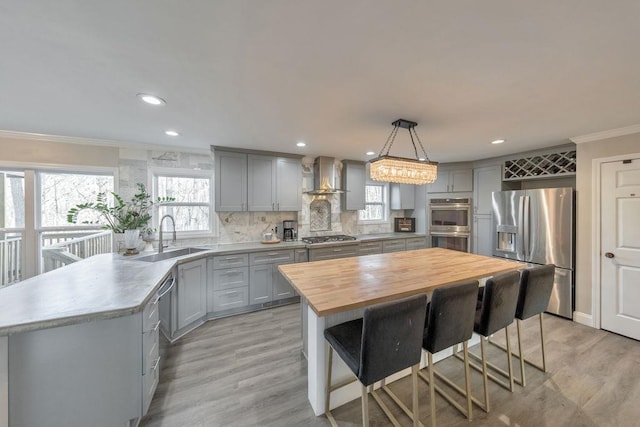 kitchen with a center island, backsplash, wall chimney range hood, decorative light fixtures, and stainless steel appliances