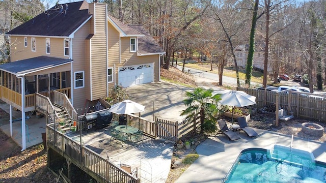 exterior space featuring a fenced in pool, a garage, and a sunroom