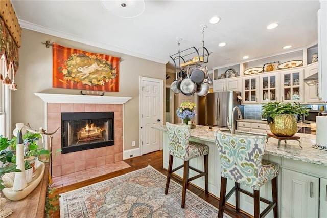 1042 Bailey Rd, Woodstock, GA 30188 - kitchen featuring freestanding refrigerator, crown molding, a kitchen breakfast bar, a peninsula, and a tiled fireplace