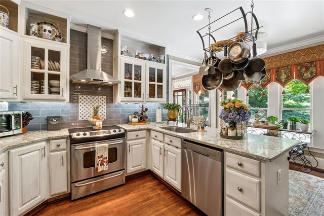 1042 Bailey Rd, Woodstock, GA 30188 - kitchen featuring appliances with stainless steel finishes, wall chimney range hood, a peninsula, crown molding, and dark wood-style floors