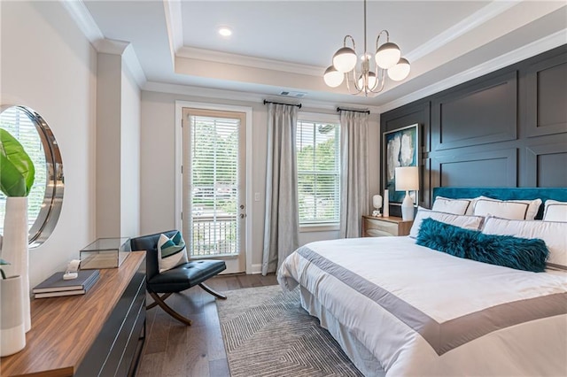 bedroom featuring crown molding, dark hardwood / wood-style flooring, access to exterior, an inviting chandelier, and a tray ceiling