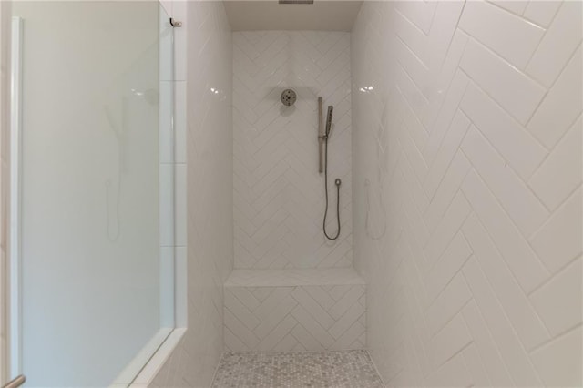 bathroom with tiled shower and tile patterned flooring