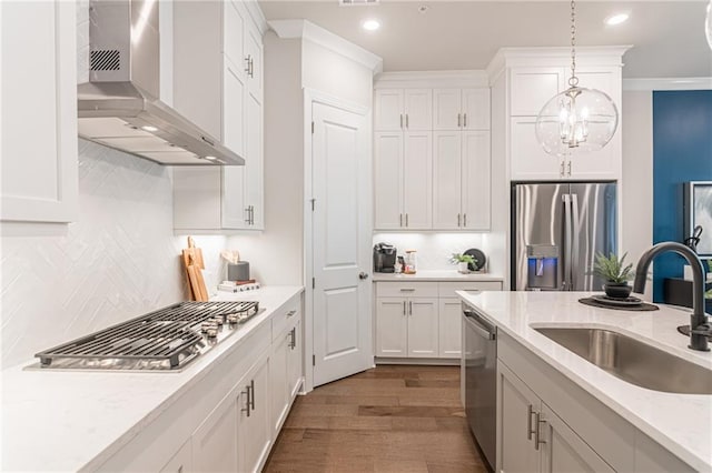 kitchen featuring decorative light fixtures, wood-type flooring, sink, wall chimney exhaust hood, and appliances with stainless steel finishes