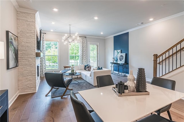 dining area with ornamental molding, an inviting chandelier, dark hardwood / wood-style flooring, and a fireplace