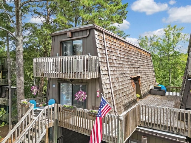 rear view of property featuring a balcony and a wooden deck