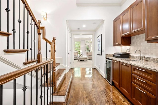 interior space featuring wine cooler, dark wood-style flooring, a sink, baseboards, and crown molding