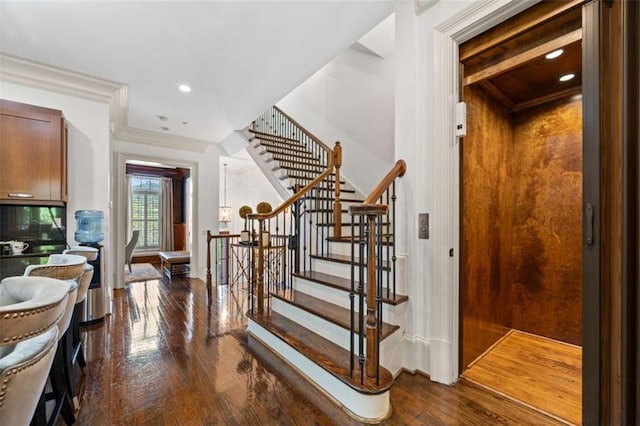 stairway featuring elevator, crown molding, hardwood / wood-style flooring, and recessed lighting
