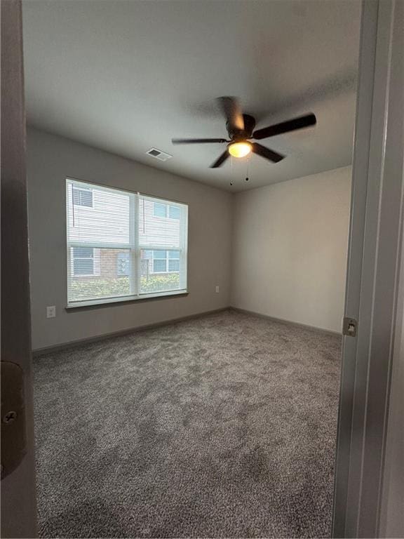 carpeted spare room with ceiling fan and visible vents