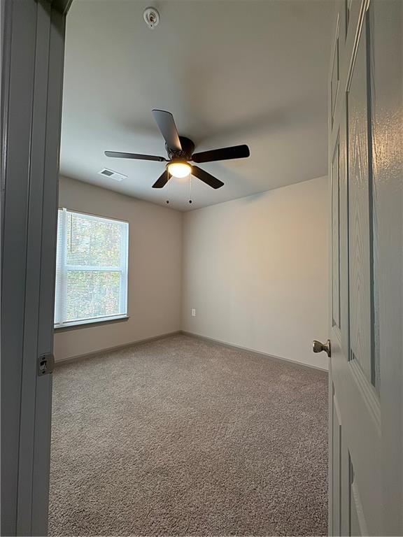 unfurnished room with baseboards, visible vents, ceiling fan, and carpet flooring