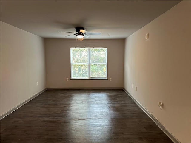 unfurnished room featuring dark wood-style flooring, ceiling fan, and baseboards