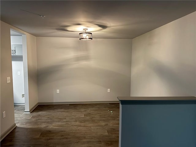 spare room with baseboards and dark wood-type flooring