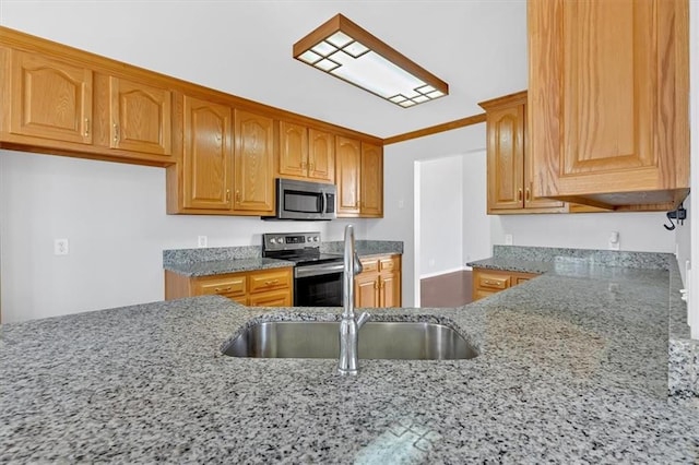 kitchen featuring brown cabinetry, a sink, light stone counters, and appliances with stainless steel finishes