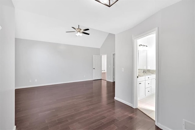 interior space with ensuite bath, vaulted ceiling, visible vents, baseboards, and dark wood-style floors