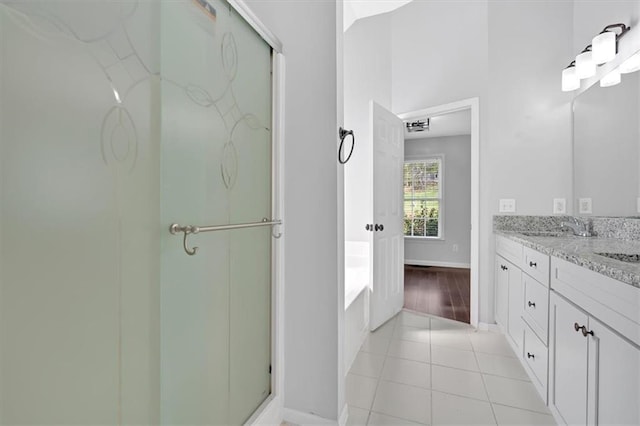 bathroom with baseboards, a sink, a shower stall, double vanity, and tile patterned floors